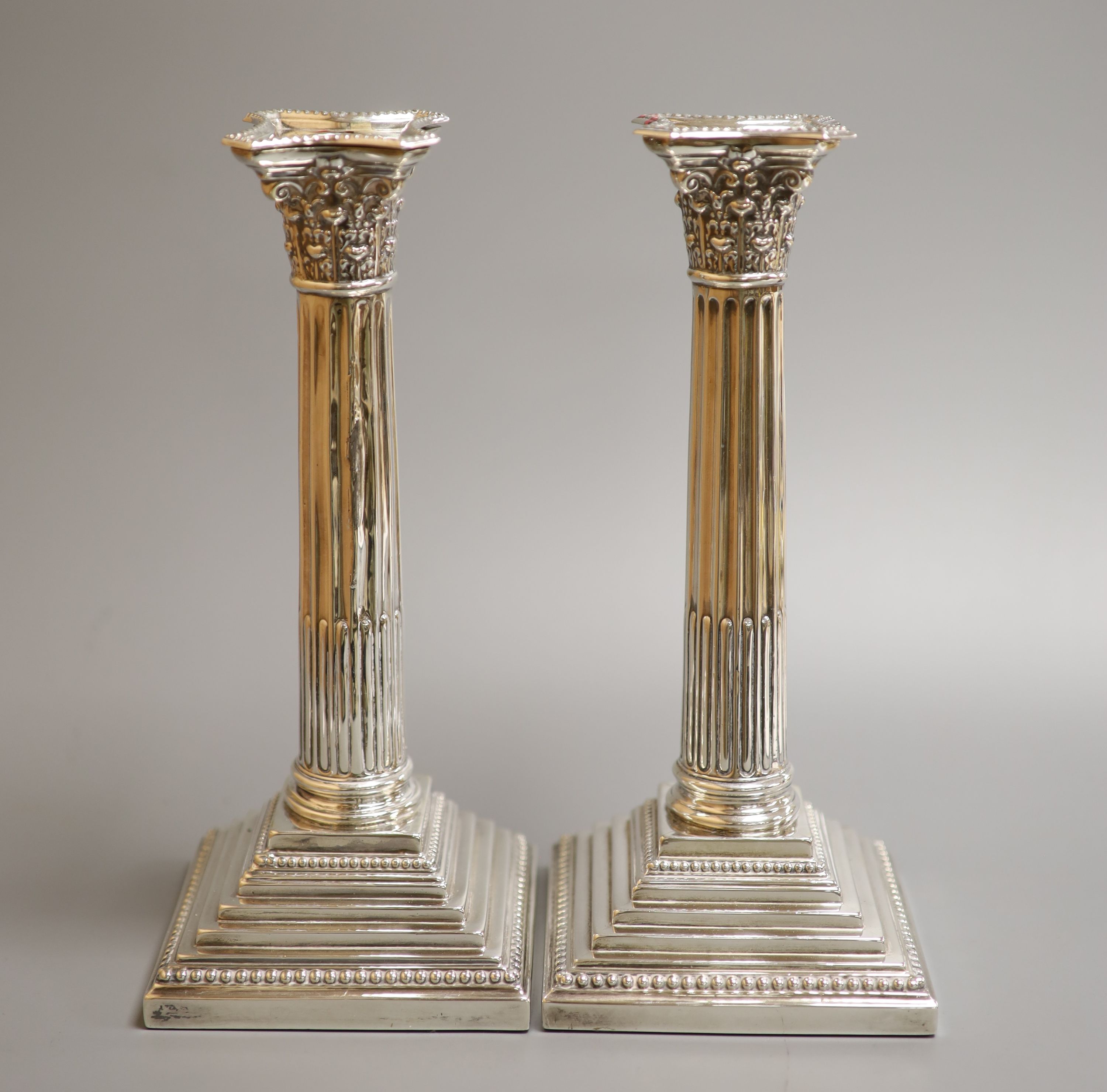 A pair of Edwardian silver Corinthian column candlesticks by Williams (Birmingham) Ltd, Birmingham, 1903, height 24.5cm, weighted, (a.f.)